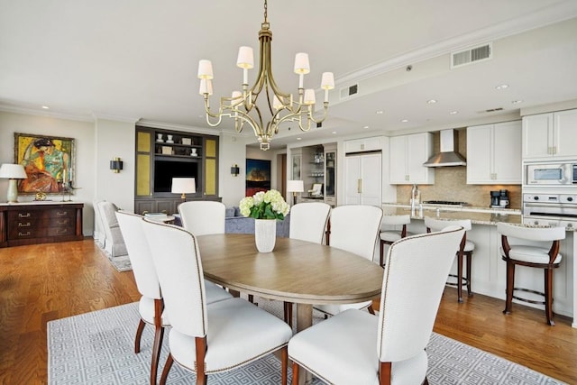 dining space featuring wood-type flooring, crown molding, and a chandelier