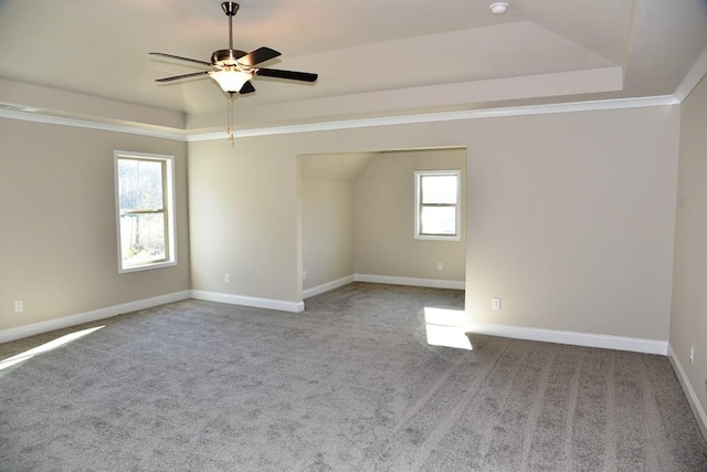 empty room with baseboards, a ceiling fan, carpet, and a tray ceiling