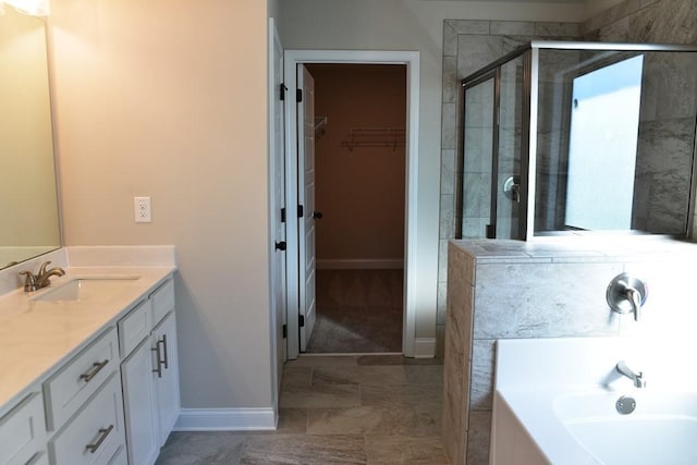 full bath with baseboards, a shower stall, a bath, vanity, and a walk in closet