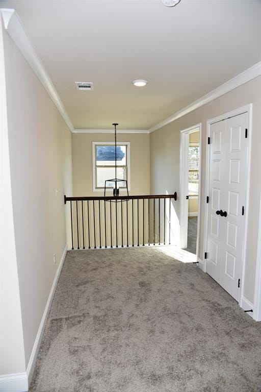 carpeted empty room with crown molding, visible vents, and baseboards
