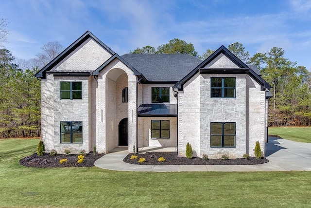 french provincial home with brick siding, stone siding, a front lawn, and a shingled roof
