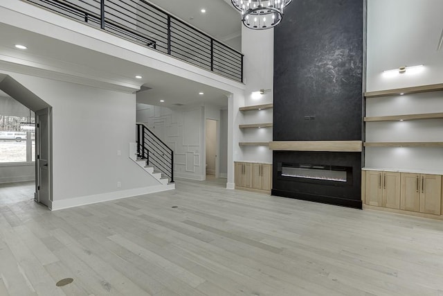 unfurnished living room with light wood-type flooring, baseboards, and stairs