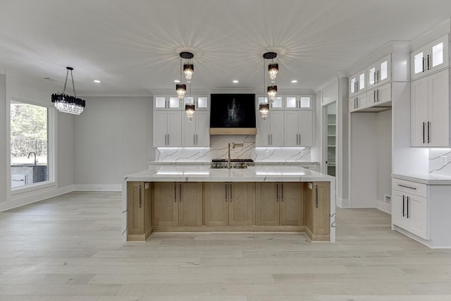 kitchen featuring white cabinets, baseboards, a spacious island, and light wood finished floors
