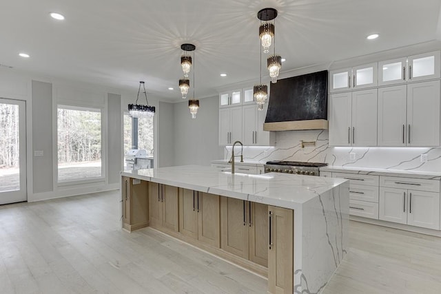 kitchen with a spacious island, light wood-style flooring, range, and custom range hood