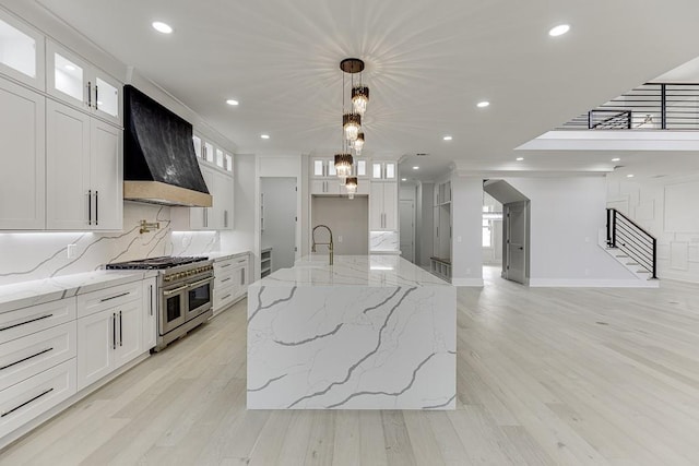 kitchen with recessed lighting, light wood finished floors, wall chimney range hood, decorative backsplash, and range with two ovens