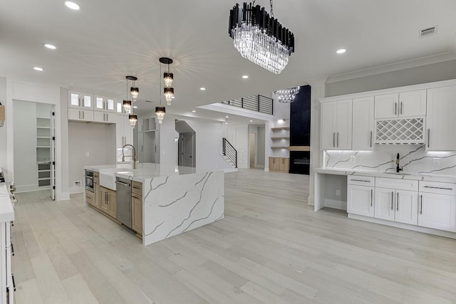 kitchen featuring a sink, a chandelier, stainless steel appliances, white cabinetry, and ornamental molding