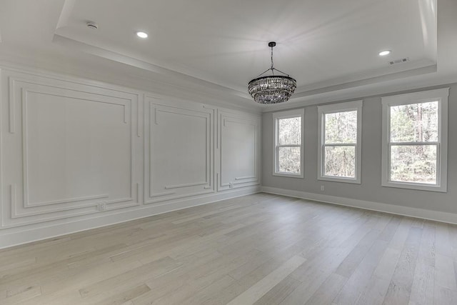 unfurnished dining area with a chandelier, a raised ceiling, plenty of natural light, and visible vents
