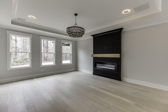unfurnished living room featuring visible vents, plenty of natural light, and a tray ceiling
