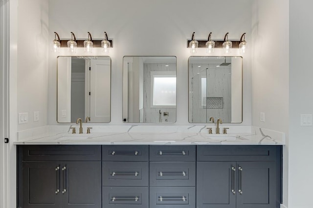 bathroom with a marble finish shower, a sink, and double vanity