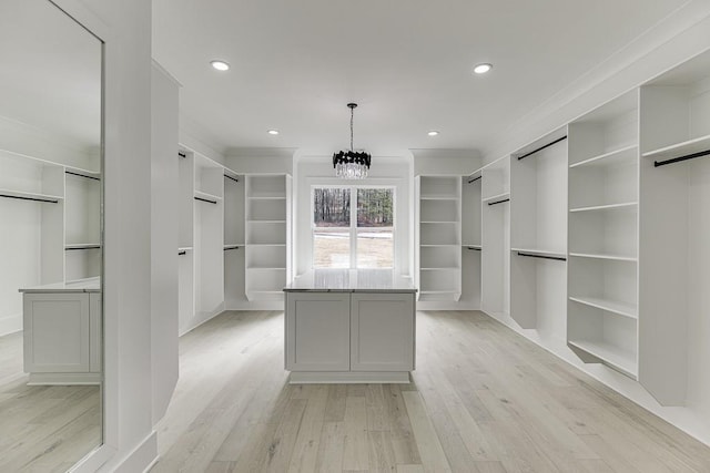 walk in closet featuring light wood-style flooring and a notable chandelier