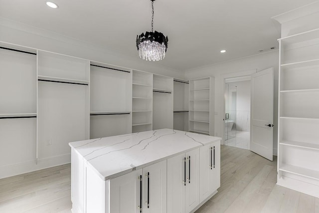 spacious closet with light wood finished floors, visible vents, and an inviting chandelier