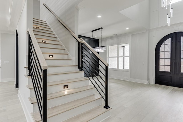 foyer entrance with light wood-style floors, stairs, baseboards, and french doors