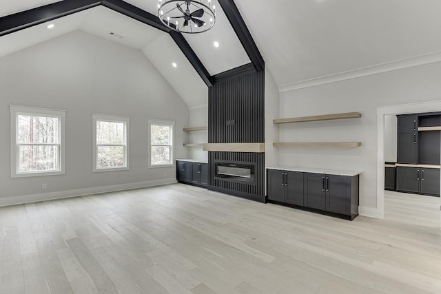 unfurnished living room with high vaulted ceiling, a glass covered fireplace, light wood finished floors, baseboards, and recessed lighting