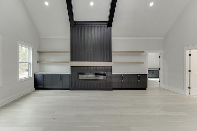unfurnished living room featuring light wood finished floors, vaulted ceiling, and baseboards
