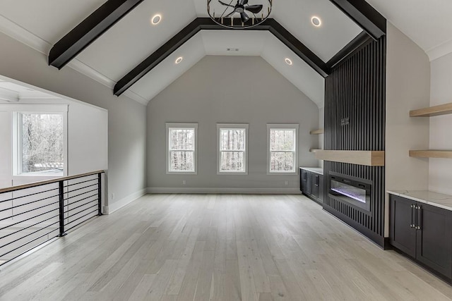 unfurnished living room featuring recessed lighting, light wood finished floors, beamed ceiling, a glass covered fireplace, and a notable chandelier