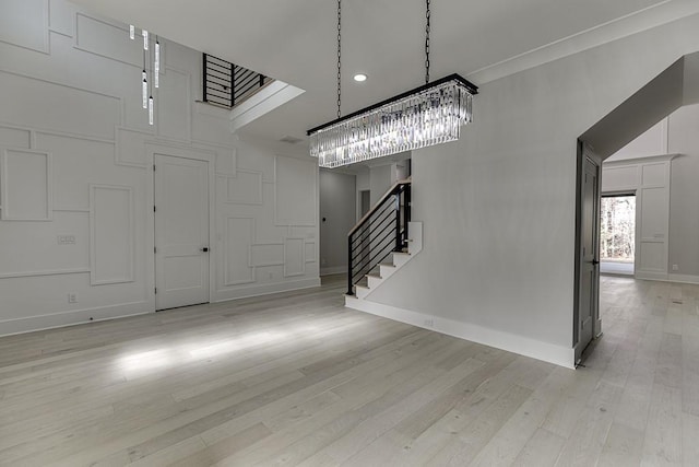 entryway featuring stairway, light wood finished floors, baseboards, a high ceiling, and a notable chandelier