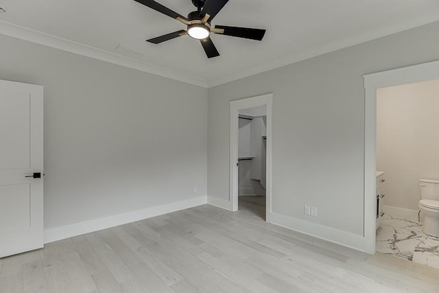 unfurnished bedroom featuring light wood-type flooring, ensuite bathroom, baseboards, a ceiling fan, and crown molding