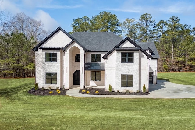 french country style house featuring a standing seam roof, driveway, a balcony, and a front yard