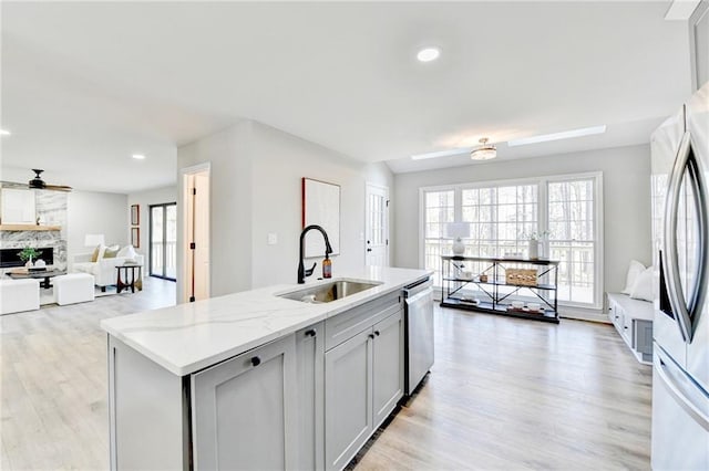 kitchen featuring a sink, light wood-style floors, stainless steel appliances, and open floor plan