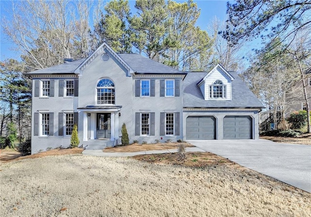 view of front of property featuring brick siding, driveway, and a garage