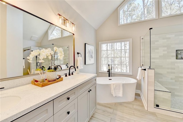 full bath with double vanity, a sink, a freestanding tub, and tiled shower