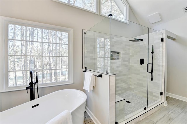 full bath with baseboards, lofted ceiling, visible vents, a soaking tub, and a stall shower