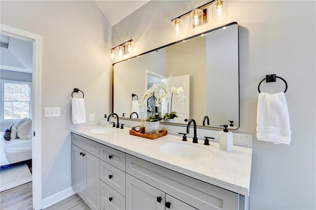 ensuite bathroom featuring double vanity, a sink, connected bathroom, and lofted ceiling