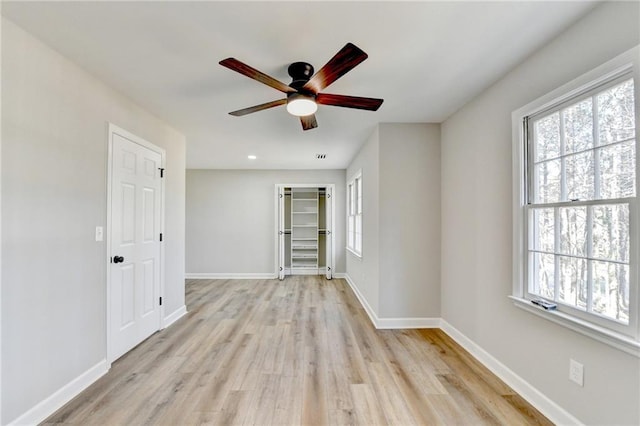 empty room with a healthy amount of sunlight, ceiling fan, and light wood finished floors