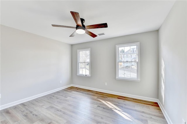 unfurnished room with baseboards, light wood finished floors, and visible vents
