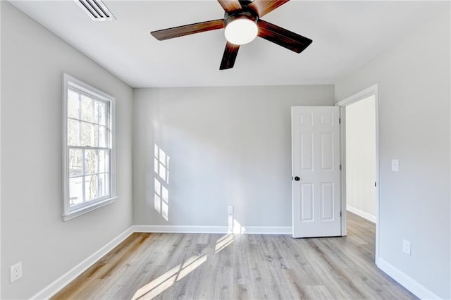 empty room featuring a ceiling fan, baseboards, visible vents, and wood finished floors