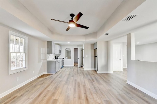 unfurnished living room with visible vents, light wood finished floors, ceiling fan, and baseboards