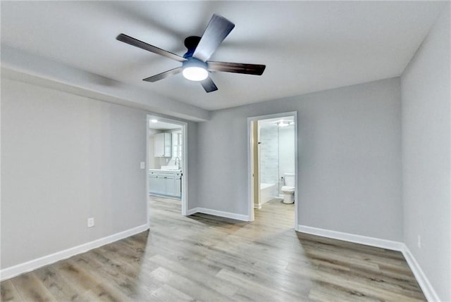 spare room featuring baseboards, a ceiling fan, a sink, and light wood finished floors