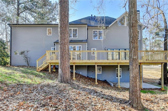 back of house with a chimney, stairs, and a wooden deck