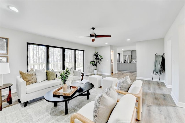 living area with baseboards, recessed lighting, ceiling fan, and light wood-style flooring