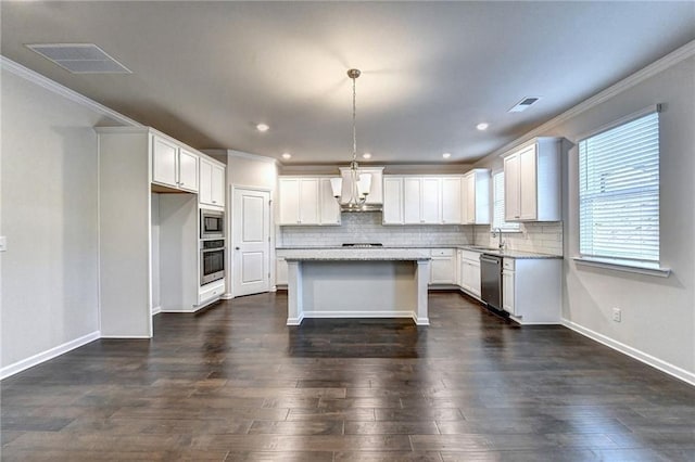 kitchen with appliances with stainless steel finishes, custom range hood, a center island, white cabinetry, and hanging light fixtures