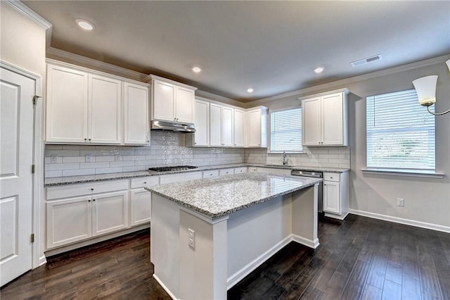 kitchen featuring decorative backsplash, light stone countertops, white cabinets, a kitchen island, and stainless steel gas stovetop