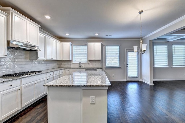 kitchen with white cabinets, stainless steel gas stovetop, light stone countertops, and hanging light fixtures