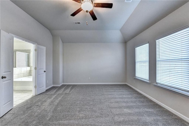 carpeted spare room featuring ceiling fan, lofted ceiling, and a wealth of natural light