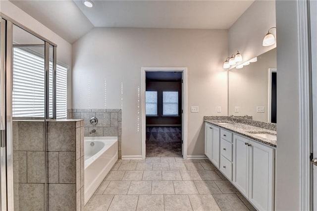 bathroom with tile patterned floors, a bathtub, lofted ceiling, and vanity