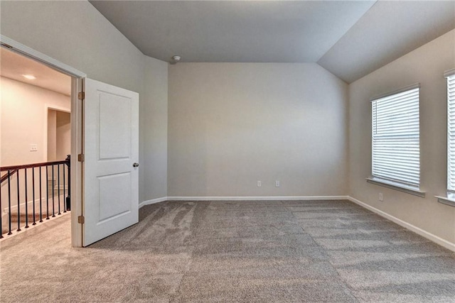 carpeted empty room with vaulted ceiling