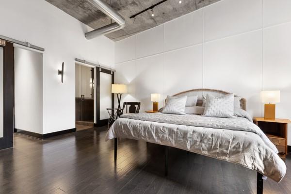 bedroom featuring a high ceiling, a barn door, and wood finished floors