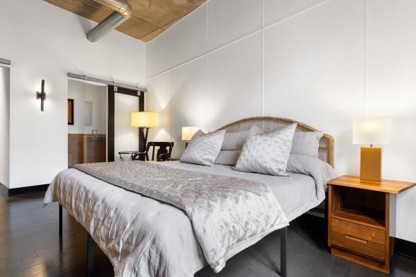 bedroom with a barn door and wood finished floors