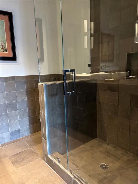full bath with a stall shower, tile patterned flooring, and tile walls