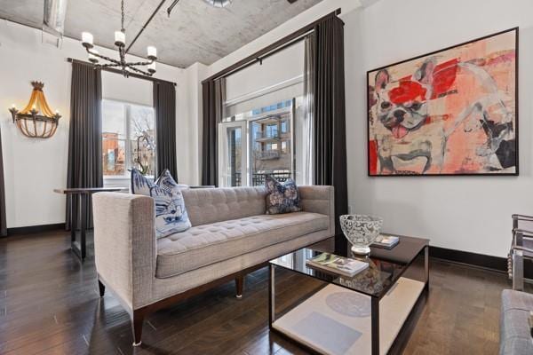 living room featuring baseboards, wood finished floors, and an inviting chandelier