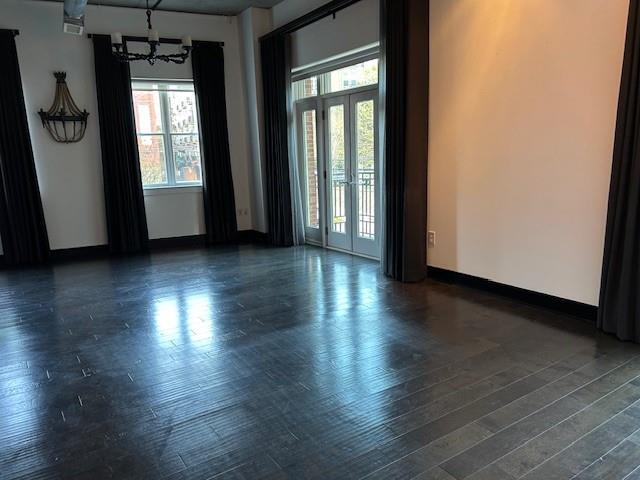 spare room featuring dark wood-type flooring, a healthy amount of sunlight, and a chandelier