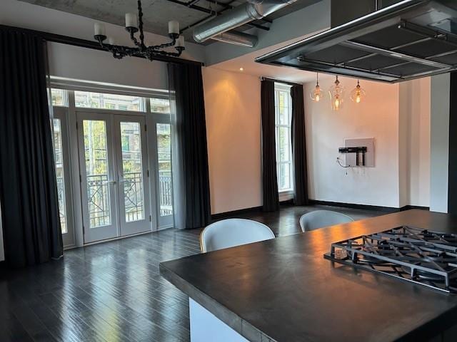 interior space featuring a notable chandelier, french doors, wood finished floors, stovetop, and exhaust hood