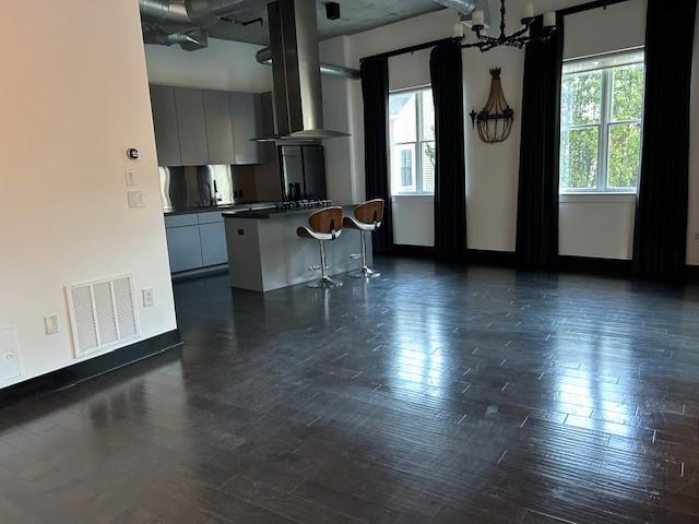 kitchen featuring dark wood-type flooring, a kitchen bar, visible vents, and plenty of natural light