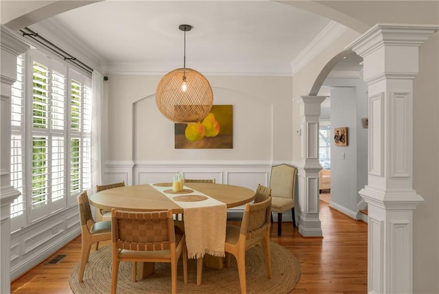 1560 Gilstrap Ln NW, Atlanta, GA 30318 - dining room featuring arched walkways, light wood-type flooring, ornate columns, wainscoting, and crown molding