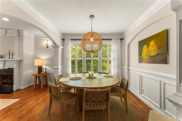 1560 Gilstrap Ln NW, Atlanta, GA 30318 - dining room with arched walkways, light wood-type flooring, crown molding, a fireplace with flush hearth, and wainscoting
