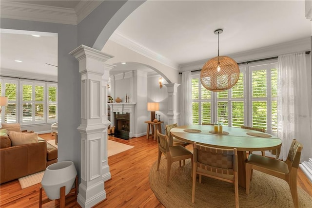 1560 Gilstrap Ln NW, Atlanta, GA 30318 - dining space featuring decorative columns, light wood-type flooring, ornamental molding, a fireplace, and arched walkways